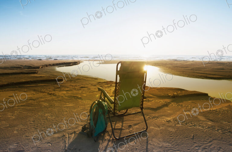 Lounge chair on beach under blue sky