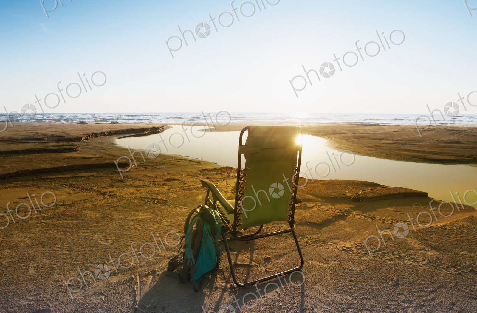 Lounge chair on beach under blue sky