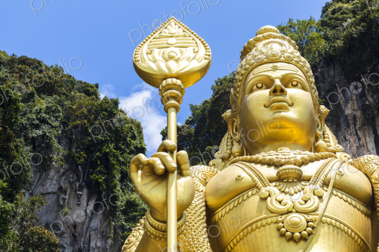 Low angle close up of colossal golden statue of Hindu deity.