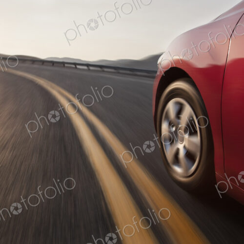 Low angle side view of a car and a tire moving on the road.