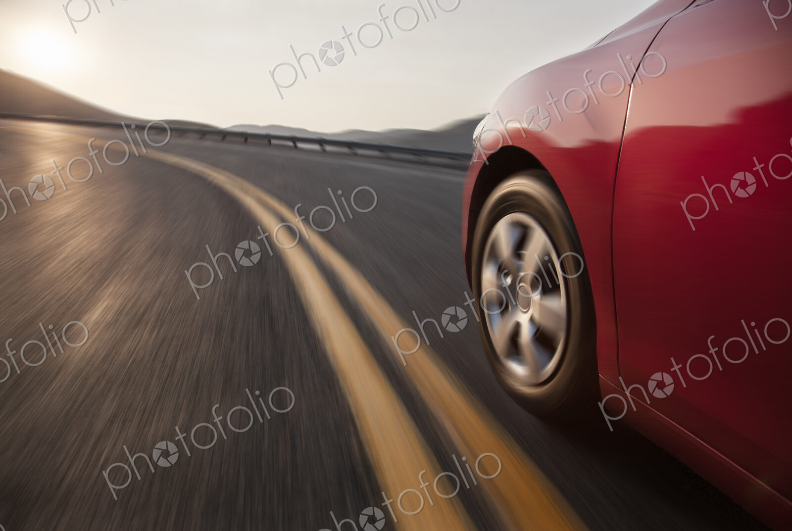 Low angle side view of a car and a tire moving on the road.