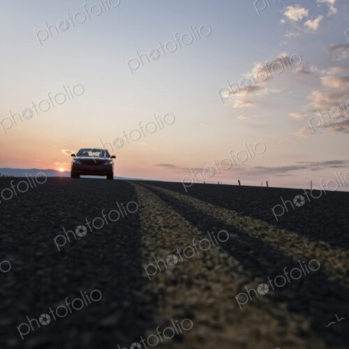 Low angle view looking up at a convertible sports car on the road at sunset. Low angle view looking up at a convertible sports car on the road at sunset.