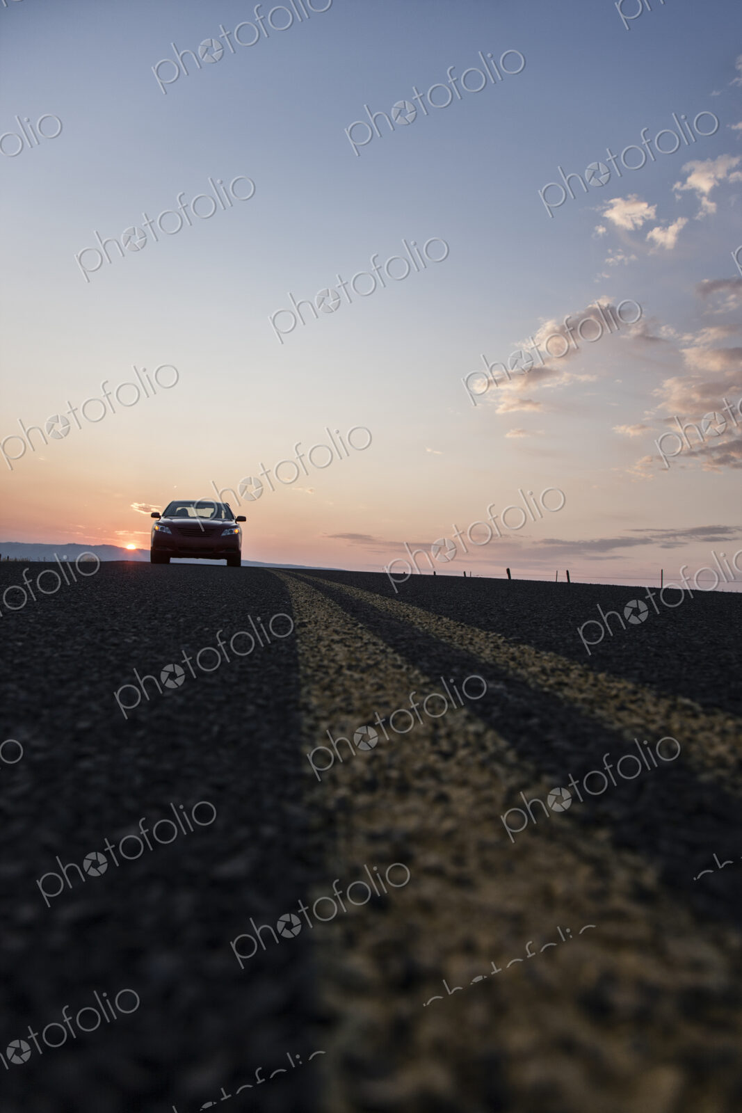 Low angle view looking up at a convertible sports car on the road at sunset.