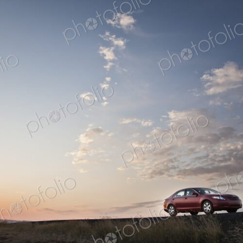 Low angle view looking up at a convertible sports car on the road at sunset.