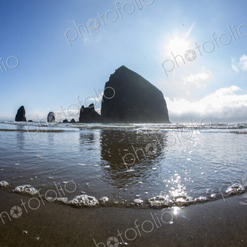Low angle view of Haystack Rock reflecting in ocean waves, Cannon Beach, Oregon,… Low angle view of Haystack Rock reflecting in ocean waves, Cannon Beach, Oregon,…