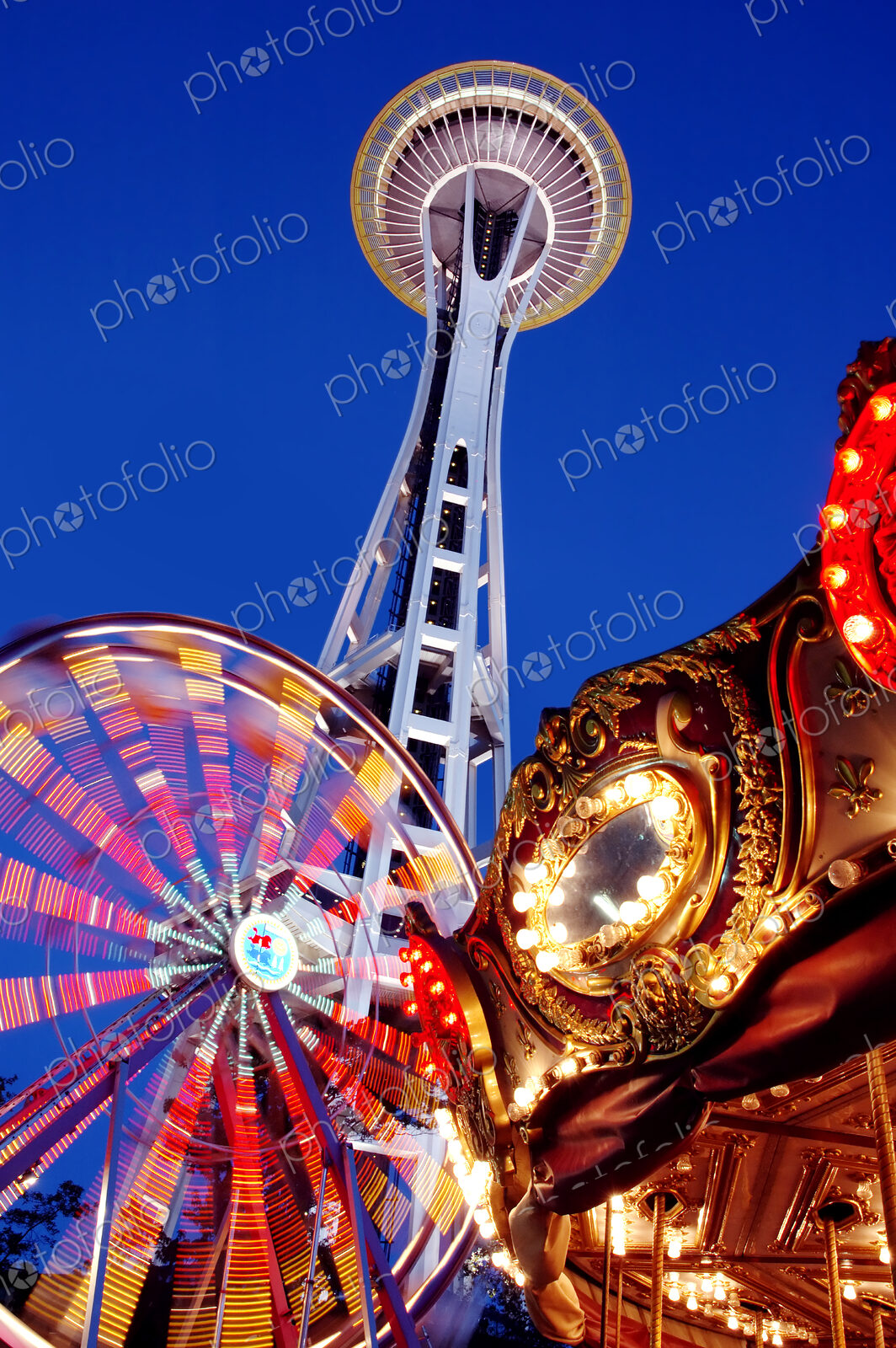 Low angle view of Space Needle, ferris wheel and carousel under night sky