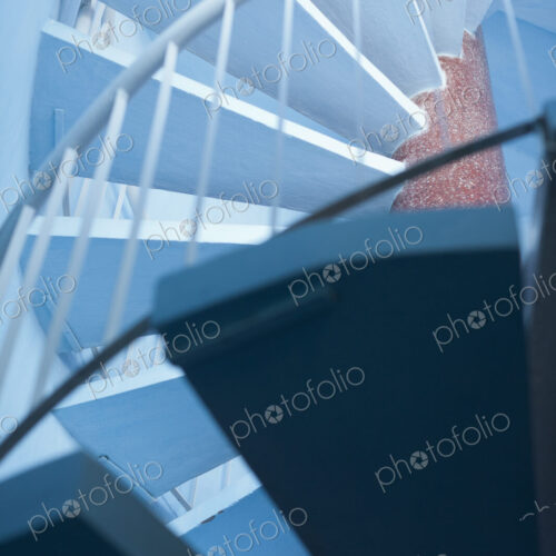 Low angle view of a blue spiral staircase with a white handrail. Low angle view of a blue spiral staircase with a white handrail.
