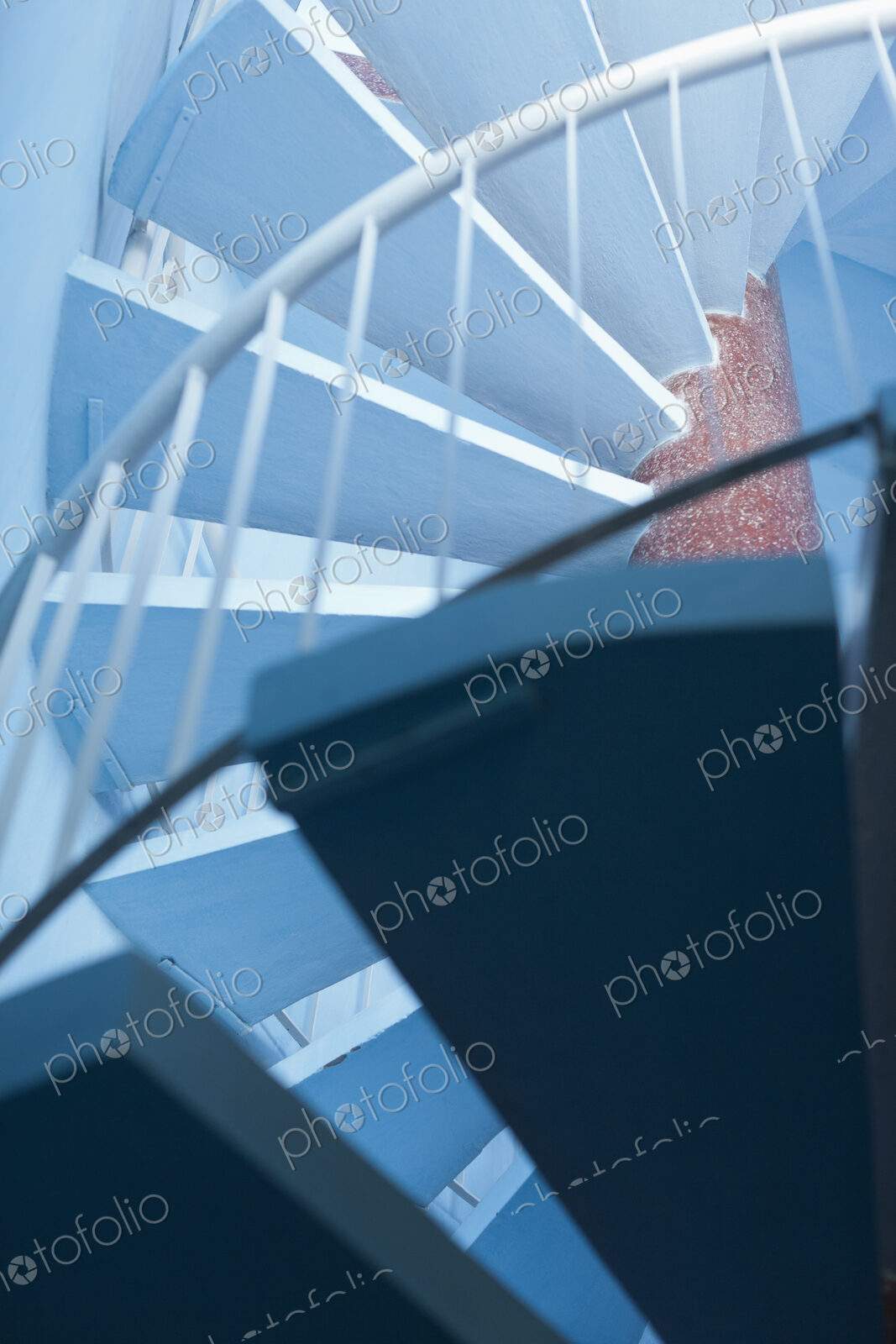 Low angle view of a blue spiral staircase with a white handrail.
