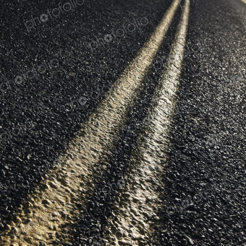 Low angle view of a double line on a highway and a car in the background. Low angle view of a double line on a highway and a car in the background.