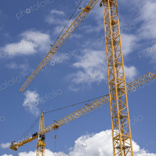 Low angle view of construction cranes under blue sky Low angle view of construction cranes under blue sky