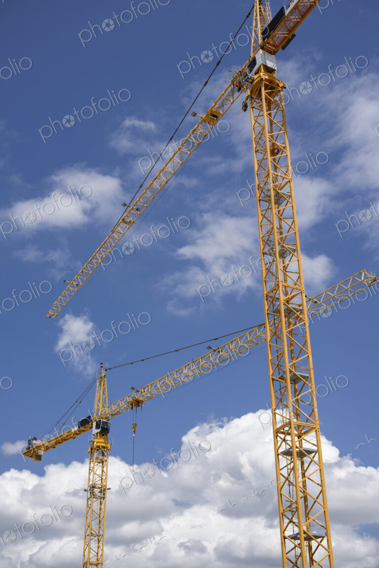 Low angle view of construction cranes under blue sky