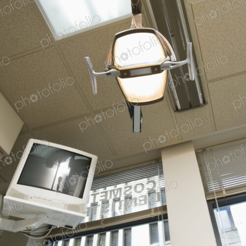 Low angle view of dentist's light and computer monitor mounted on wall.