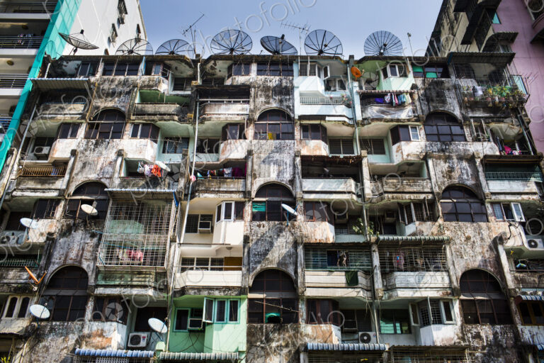 Low angle view of facade of an old apartment building, rows of balconies and windows.