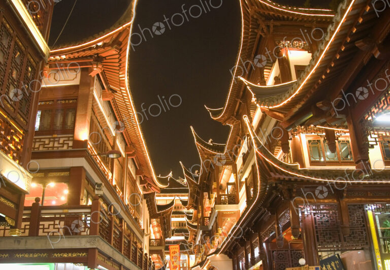 Low angle view of illuminated traditional oriental buildings with balconies at night.