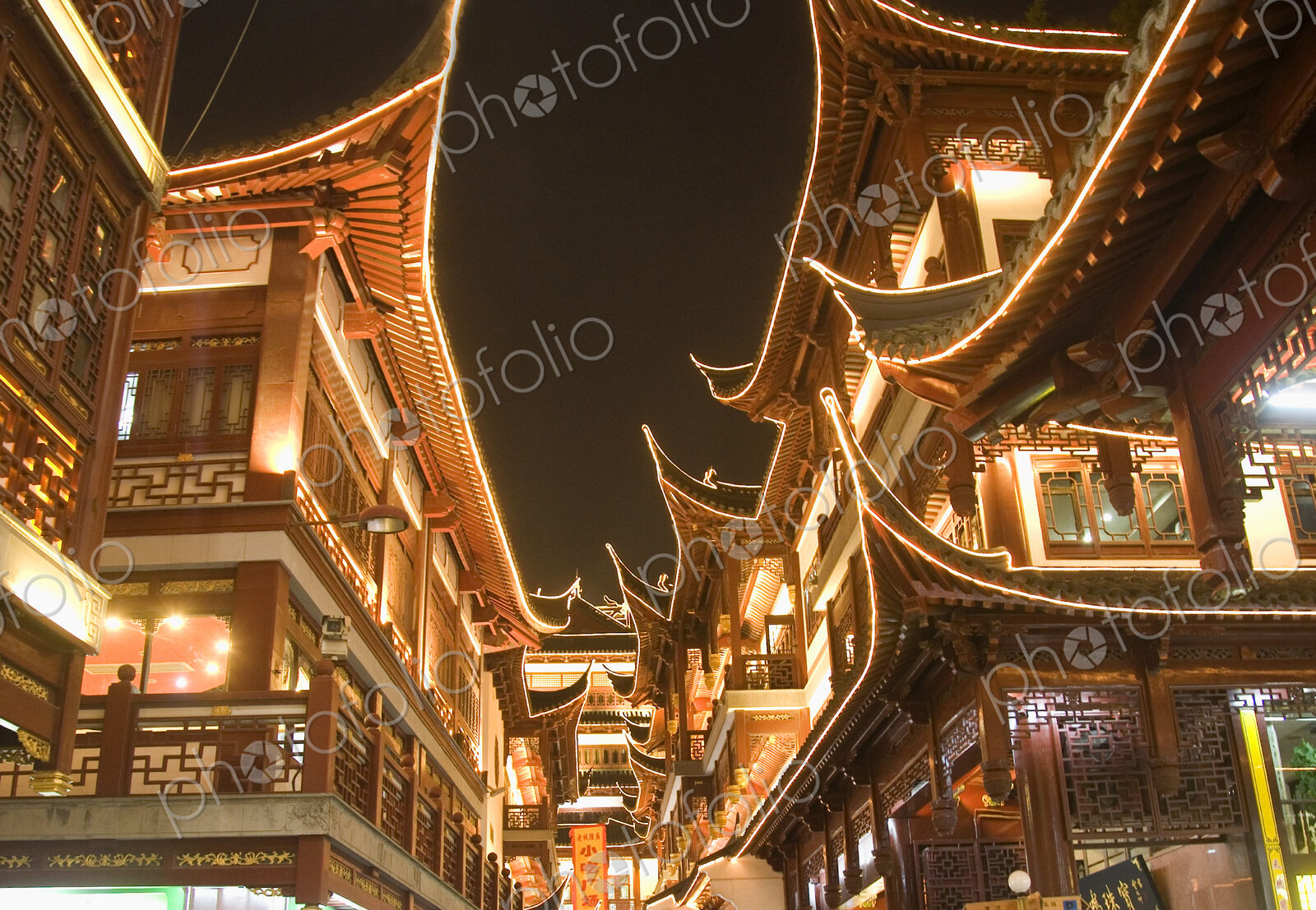 Low angle view of illuminated traditional oriental buildings with balconies at night.