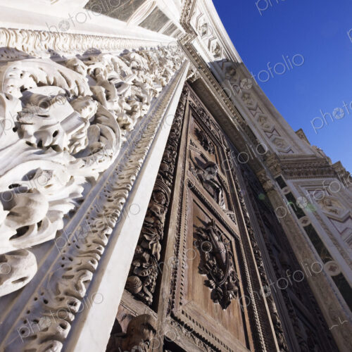Low angle view of ornate carved wooden doorway and stone building facade. Low angle view of ornate carved wooden doorway and stone building facade.
