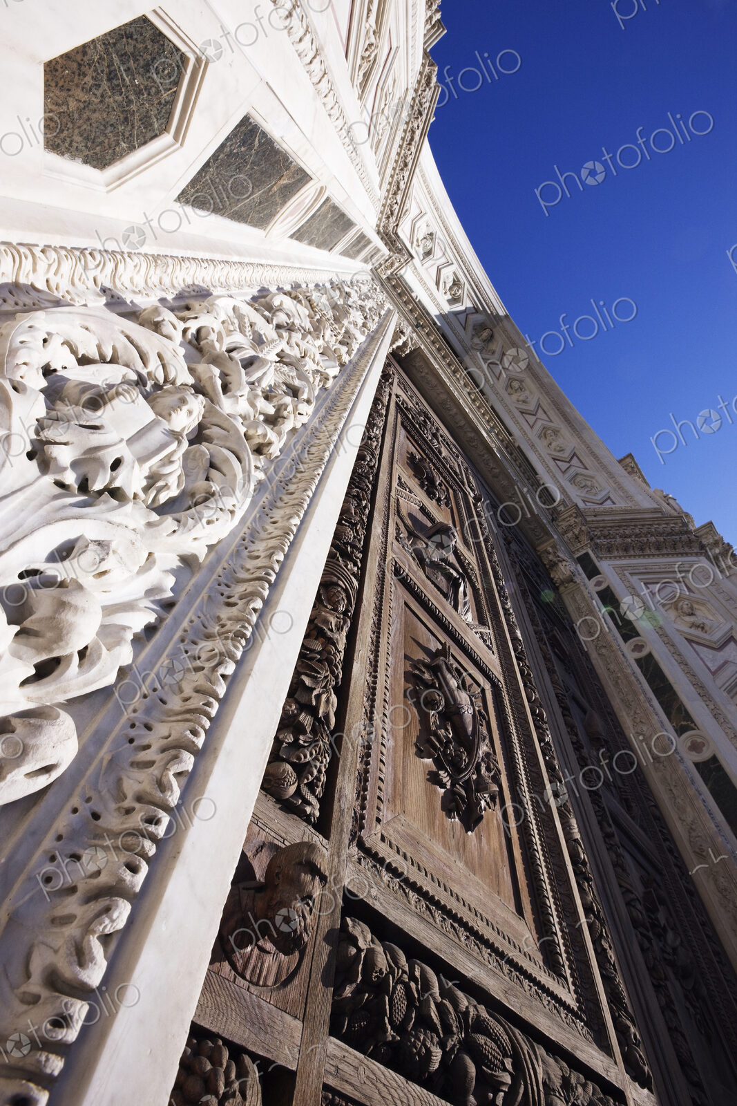 Low angle view of ornate carved wooden doorway and stone building facade.