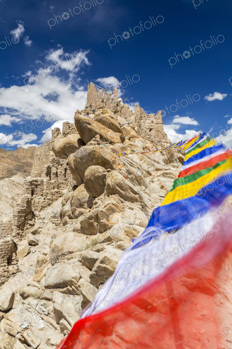 Low angle view of rock-face with colourful prayer flags.