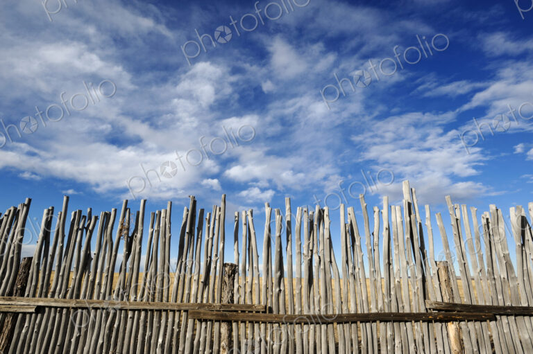 Low angle view of rustic corral fence under blue sky