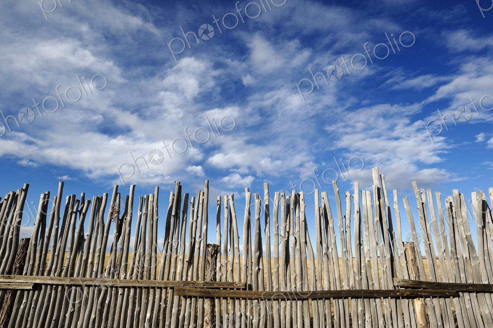 Low angle view of rustic corral fence under blue sky