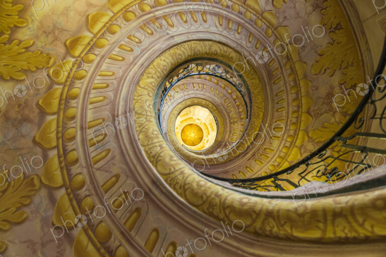 Low angle view of spiral staircase decorated with murals of golden Acanthus flowers…