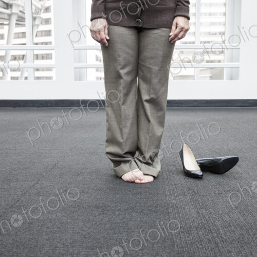 Low closeup view of a businesswoman standing on a carpet in bare feet. Low closeup view of a businesswoman standing on a carpet in bare feet.