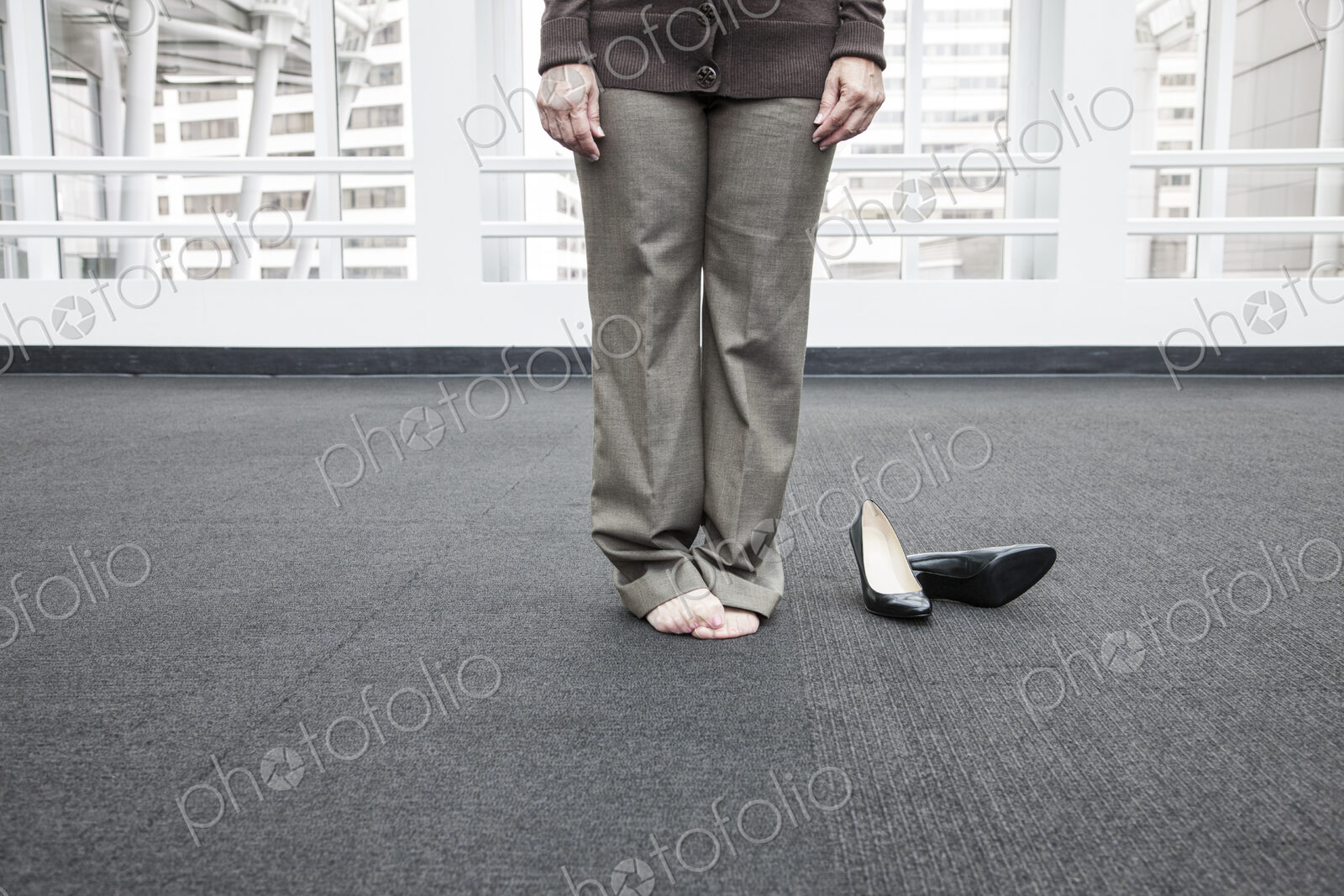 Low closeup view of a businesswoman standing on a carpet in bare feet.