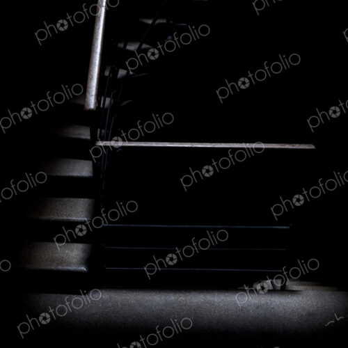 Low key detail of room with a stairway with metal handrail.