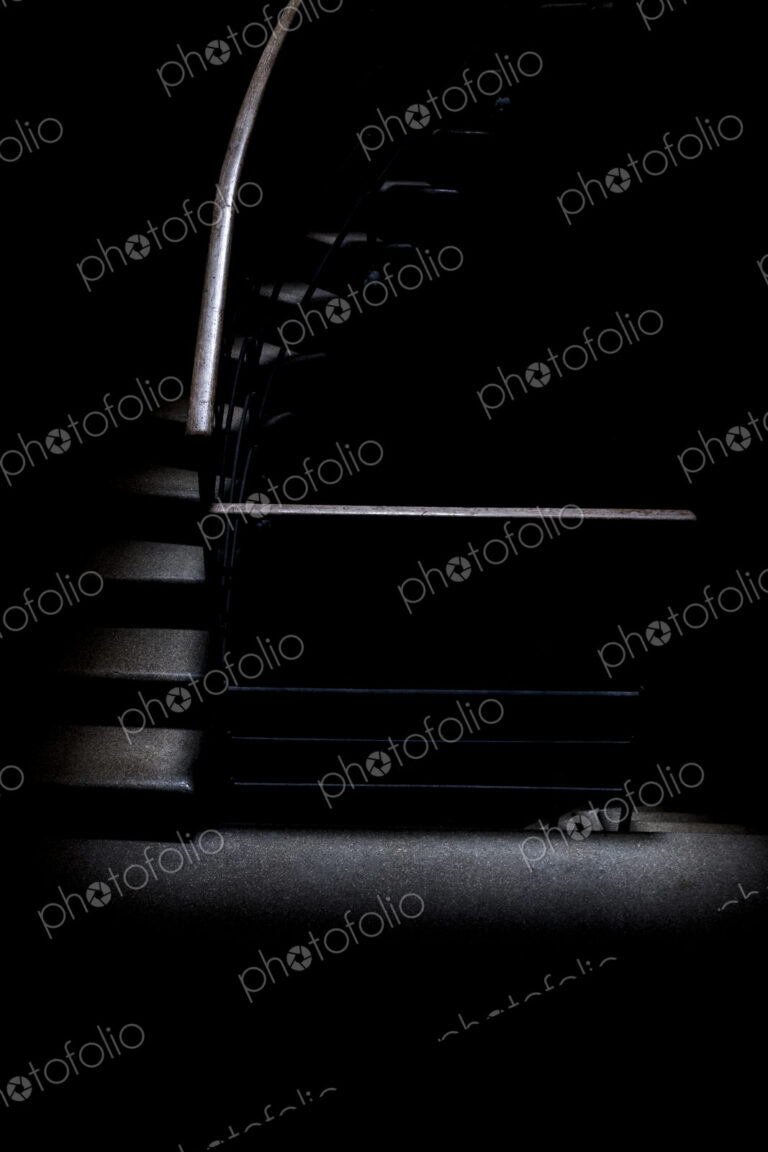 Low key detail of room with a stairway with metal handrail.
