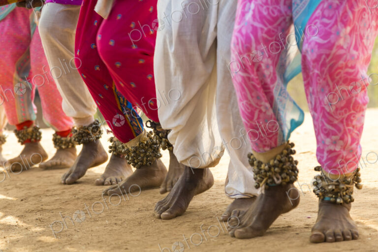 Low section view of barefoot dancers in a row on a street, wearing pink trousers and…