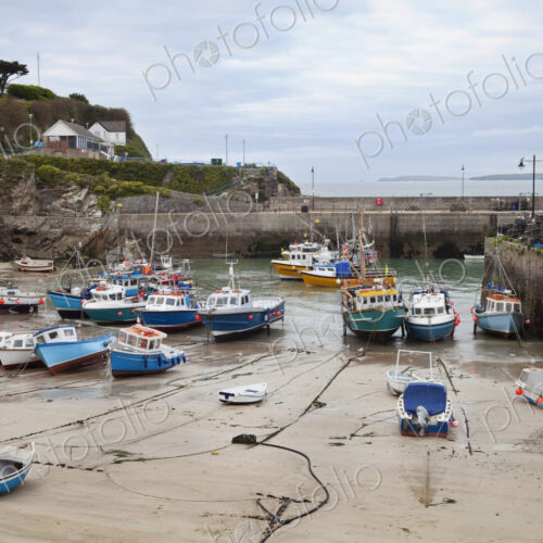 Low tide at a Cornish harbour, sea coast fishing village, boats moored, beached on the…