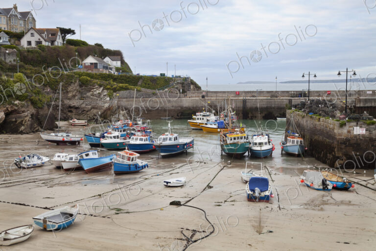 Low tide at a Cornish harbour, sea coast fishing village, boats moored, beached on the…