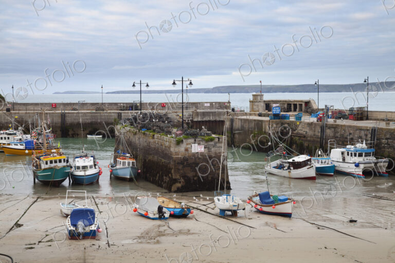 Low tide at a Cornish harbour, sea coast fishing village, boats moored, beached on the…