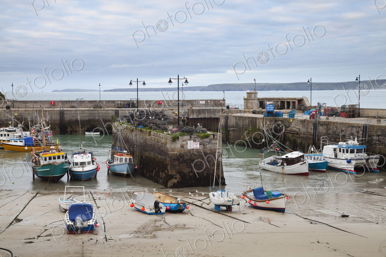 Low tide at a Cornish harbour, sea coast fishing village, boats moored, beached on the…
