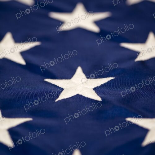 Macro detail of multiple white embroidered stars on the blue field of the American… Macro detail of multiple white embroidered stars on the blue field of the American…