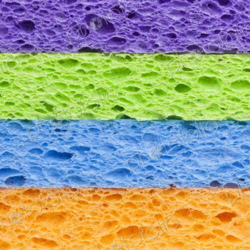 Macro image of a neatly stacked set of brightly colored synthetic cleaning sponges in…