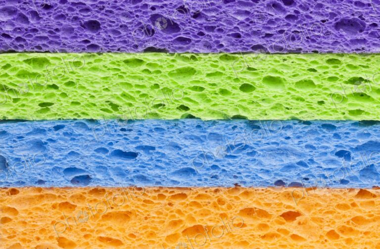 Macro image of a neatly stacked set of brightly colored synthetic cleaning sponges in…