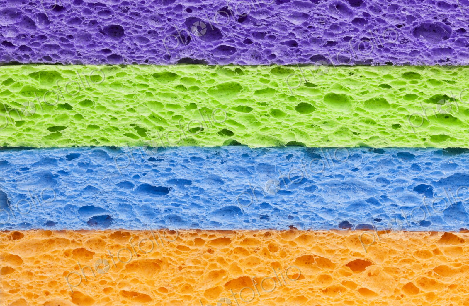 Macro image of a neatly stacked set of brightly colored synthetic cleaning sponges in…