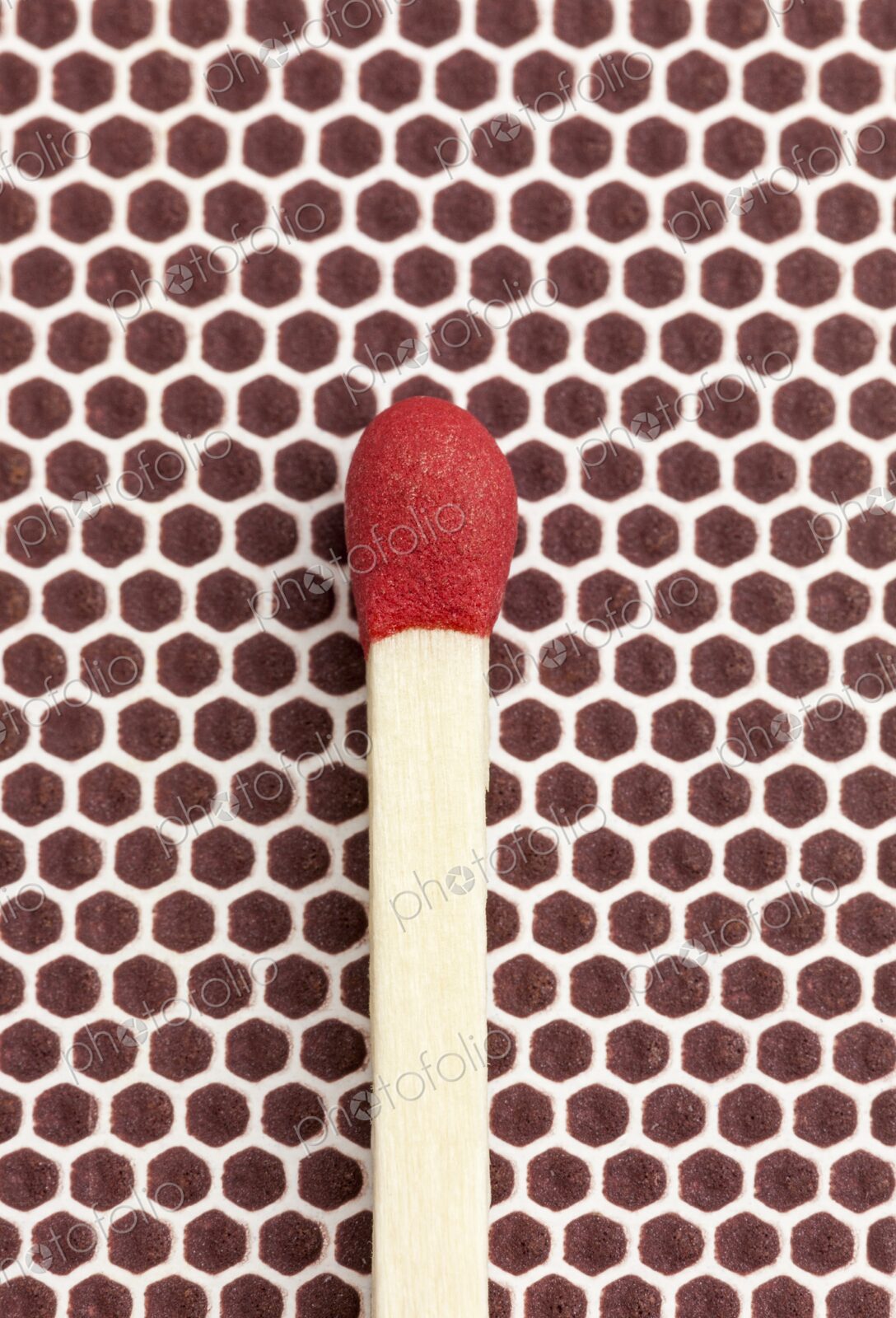 Macro photo of a single red-tipped wooden matchstick resting on the brown textured…