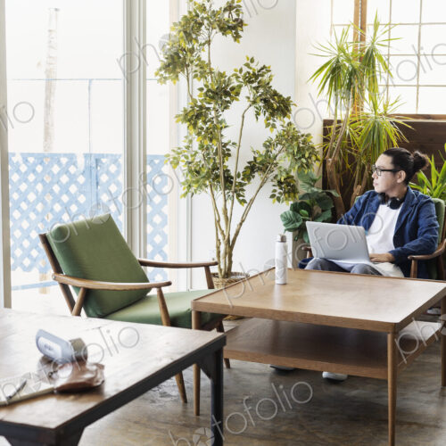 Male Japanese professional sitting at a table in a co-working space, using laptop…