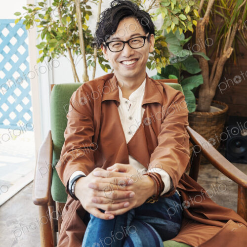 Male Japanese professional sitting in a co-working space, smiling at camera. Male Japanese professional sitting in a co-working space, smiling at camera.