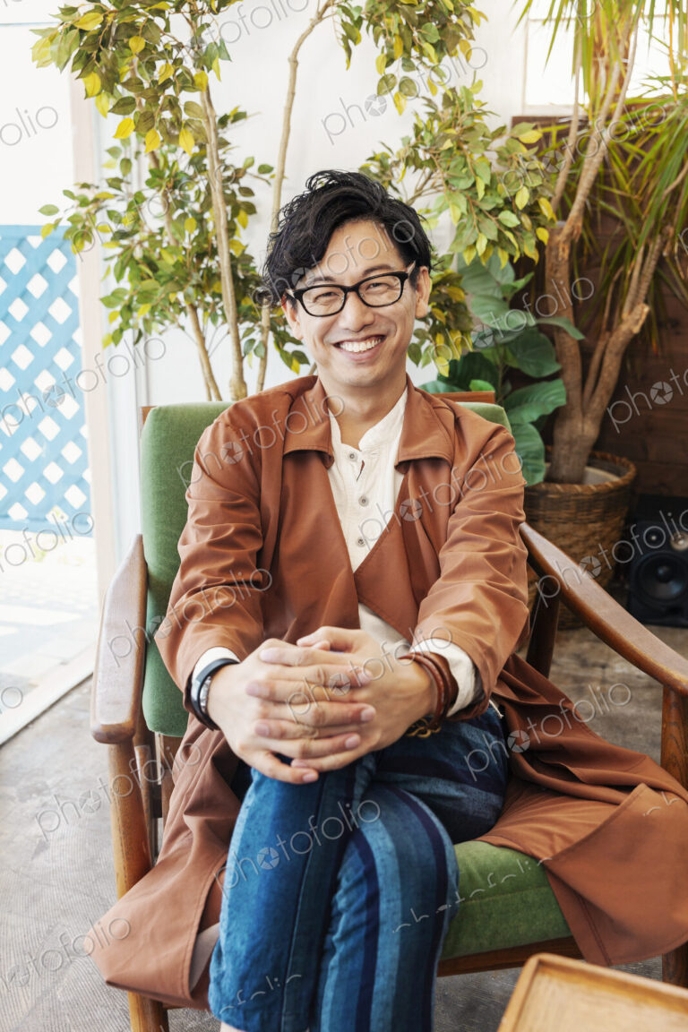 Male Japanese professional sitting in a co-working space, smiling at camera.