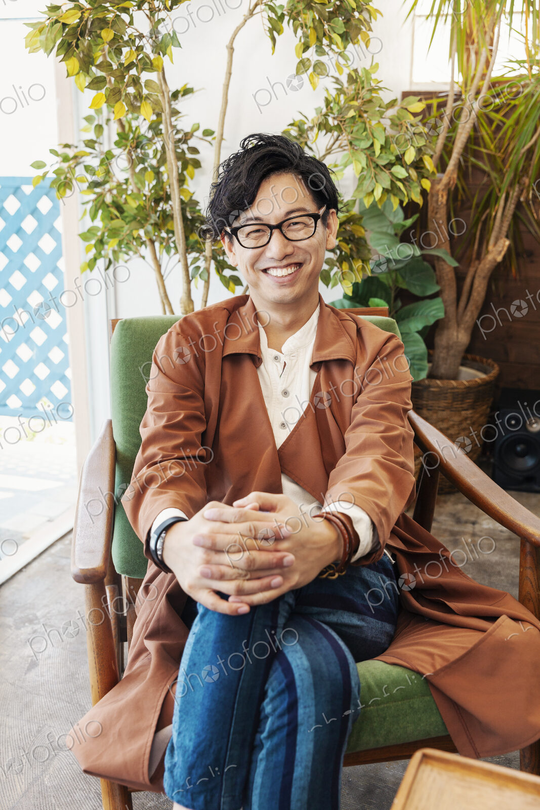 Male Japanese professional sitting in a co-working space, smiling at camera.