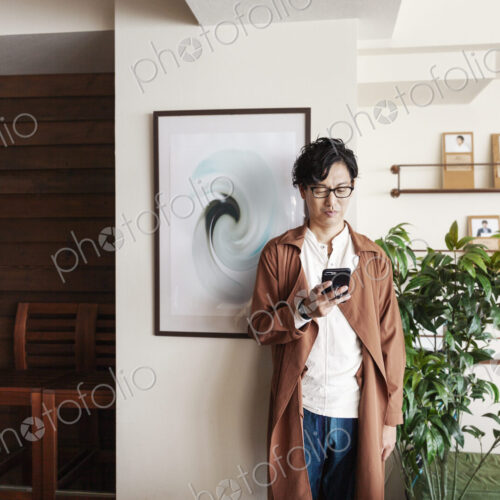Male Japanese professional standing in a co-working space, looking at his cellphone. Male Japanese professional standing in a co-working space, looking at his cellphone.