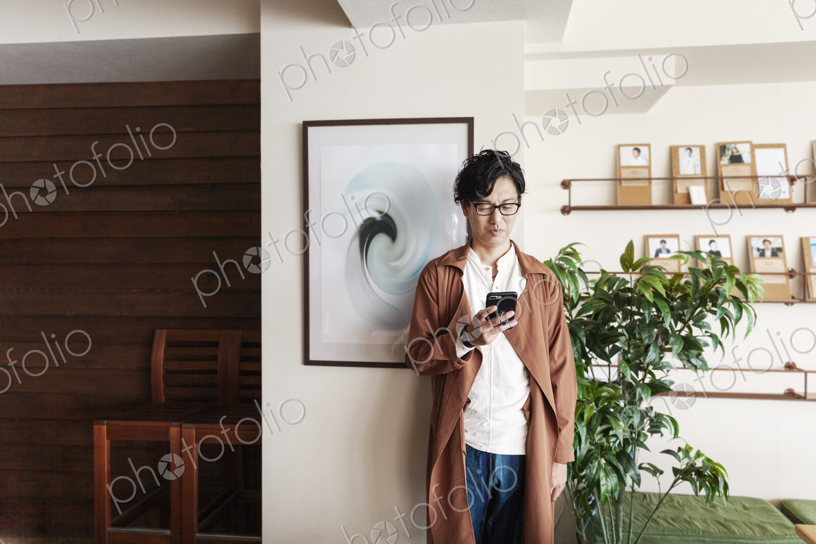 Male Japanese professional standing in a co-working space, looking at his cellphone.