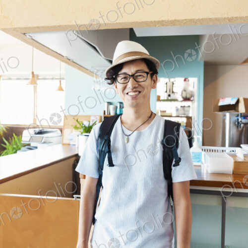 Male Japanese professional standing in a co-working space, smiling at camera.