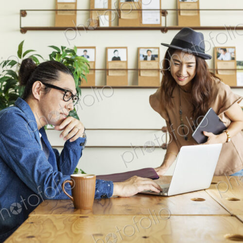 Male and female Japanese professional at a table in a co-working space, using laptop… Male and female Japanese professional at a table in a co-working space, using laptop…