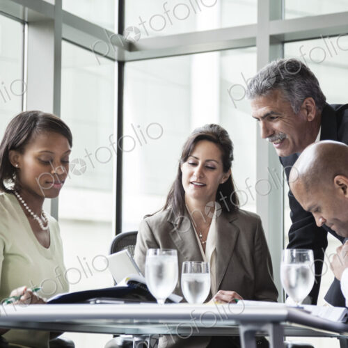 Male and female business people in a meeting at a conference table, multi ethnic group Male and female business people in a meeting at a conference table, multi ethnic group