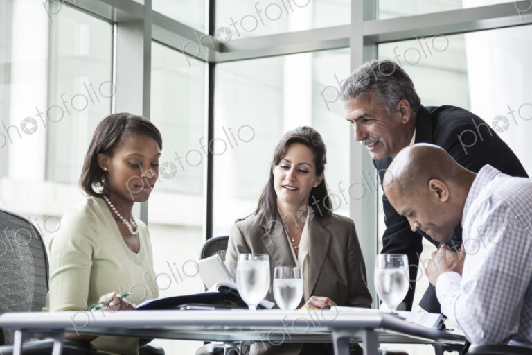 Male and female business people in a meeting at a conference table, multi ethnic group