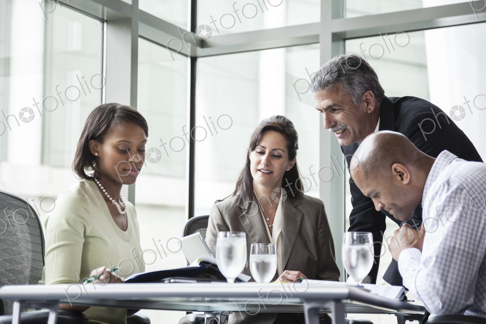 Male and female business people in a meeting at a conference table, multi ethnic group